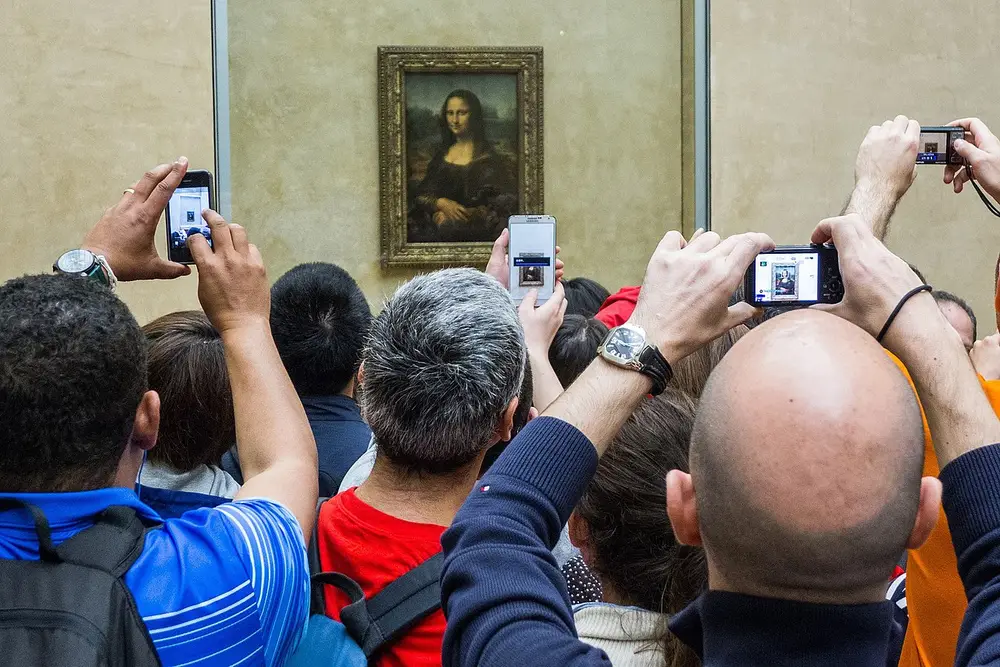 Ljudje v gneči poskušajo fotografirati sliko Mona Lisa v Louvru